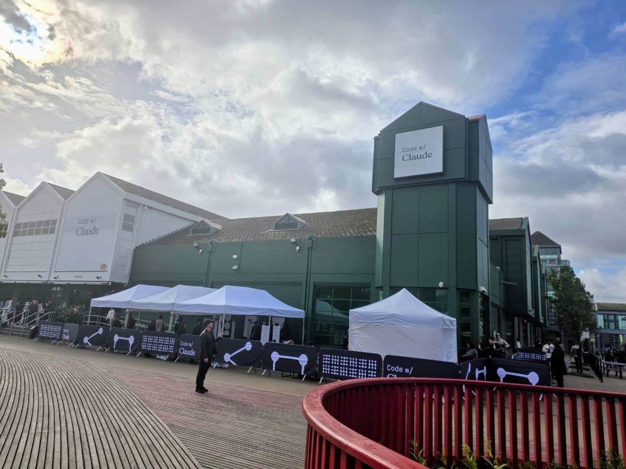 The Code w/ Claude London venue exterior, with branding and registration tents along the boardwalk.
